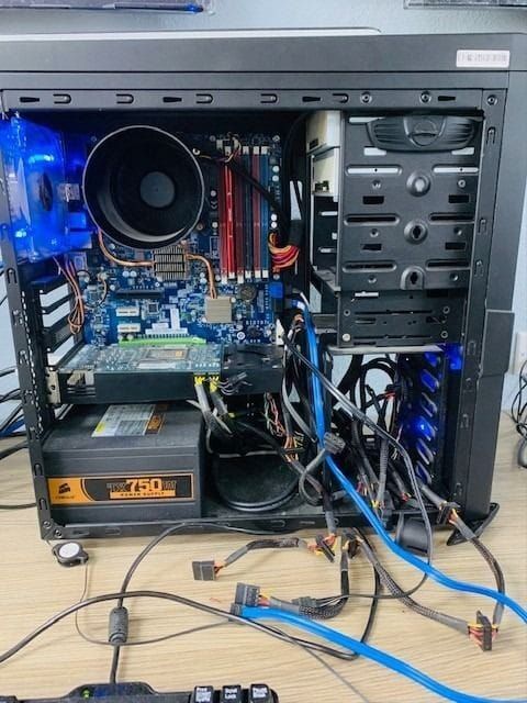 Computador desktop aberto durante manutenção, com fonte, placa de vídeo e cabos
